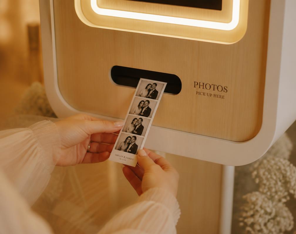 Handen die een fotostrip uit een houten fotobooth pakken